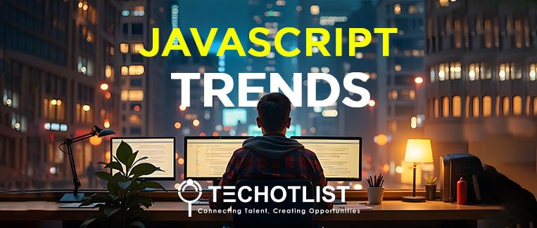 a person coding on the desktop with 3 screens, it's night time, city lights are seen, 'javascript trends' is written in capital letters.